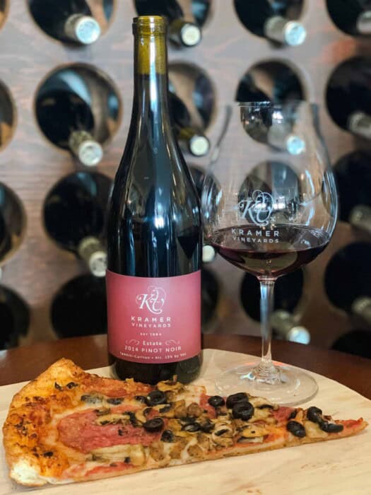 A glass of Kramer Vineyards estate Pinot Noir with a slice of pizza