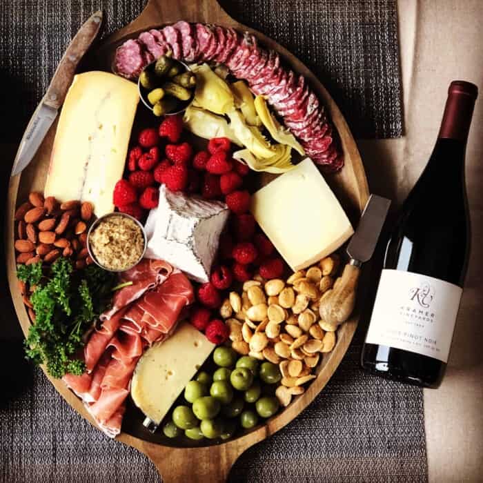 A glass of Kramer Vineyards Pinot Noir with a charcuterie and cheese board