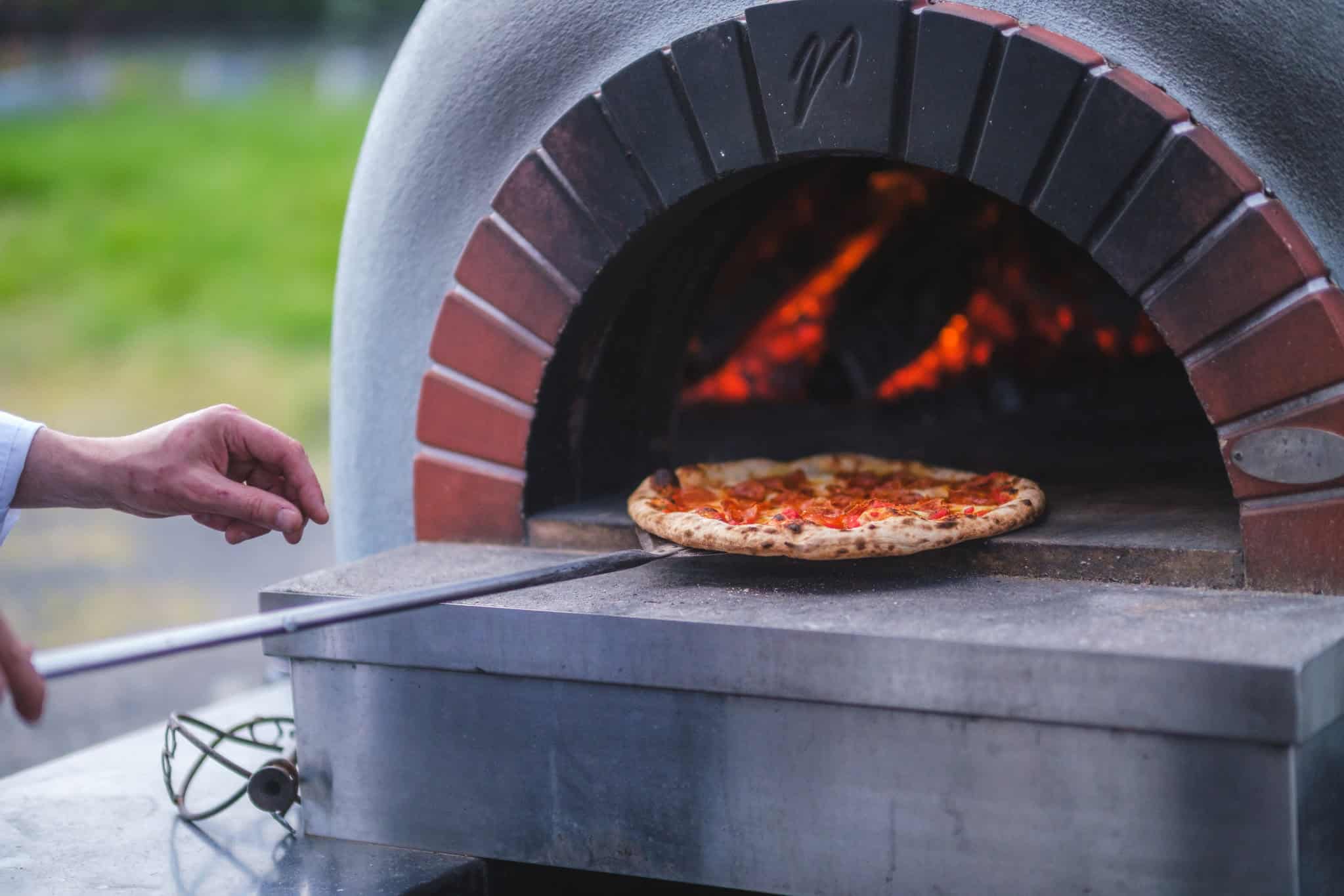 Wood-fired pizza baking in an outdoor oven during the Pizza and Pinot event at Kramer Vineyards.