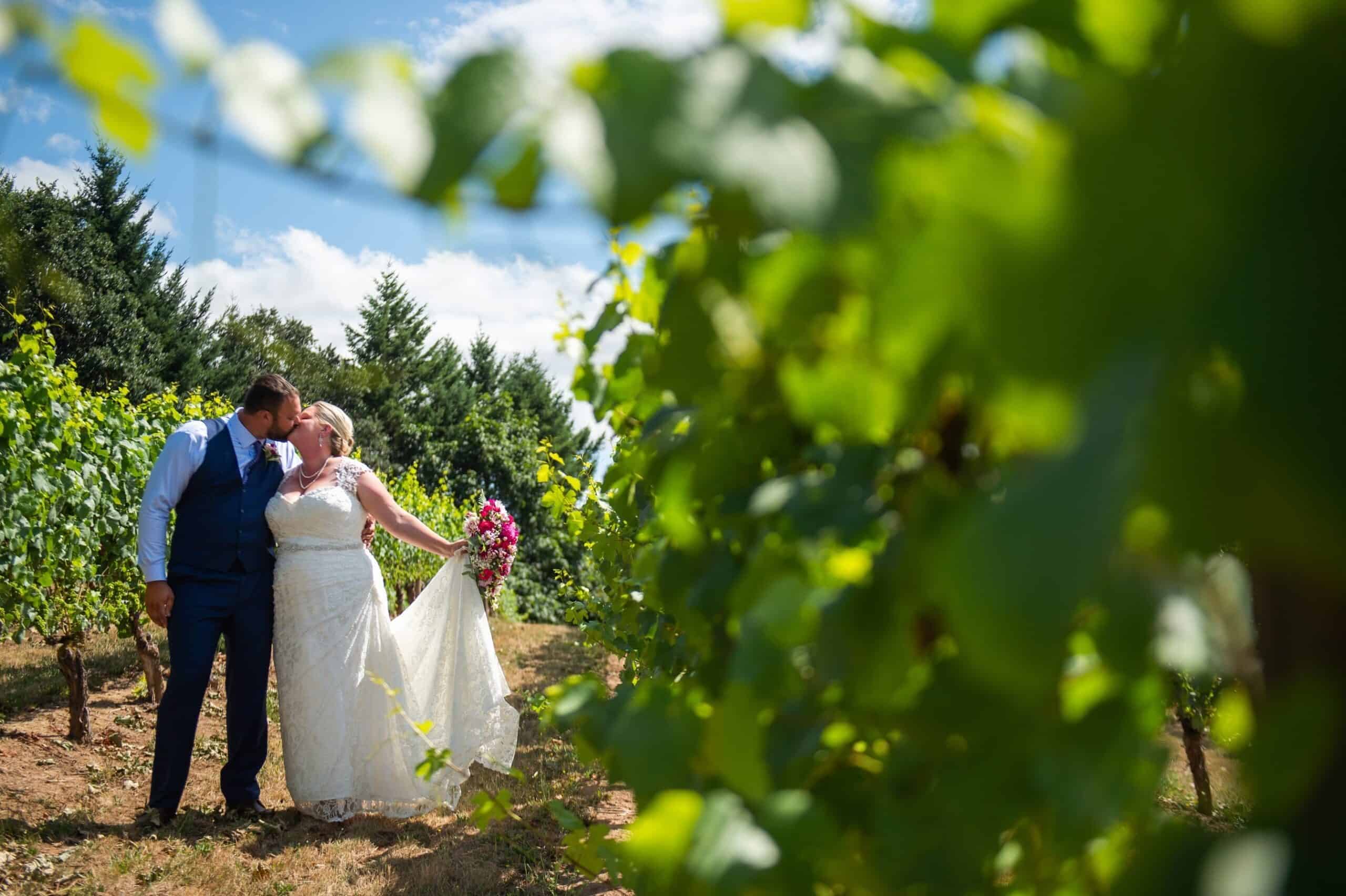 Wedding couple in vineyard at Kramer Vineyards, enjoying a romantic moment among lush grapevines.