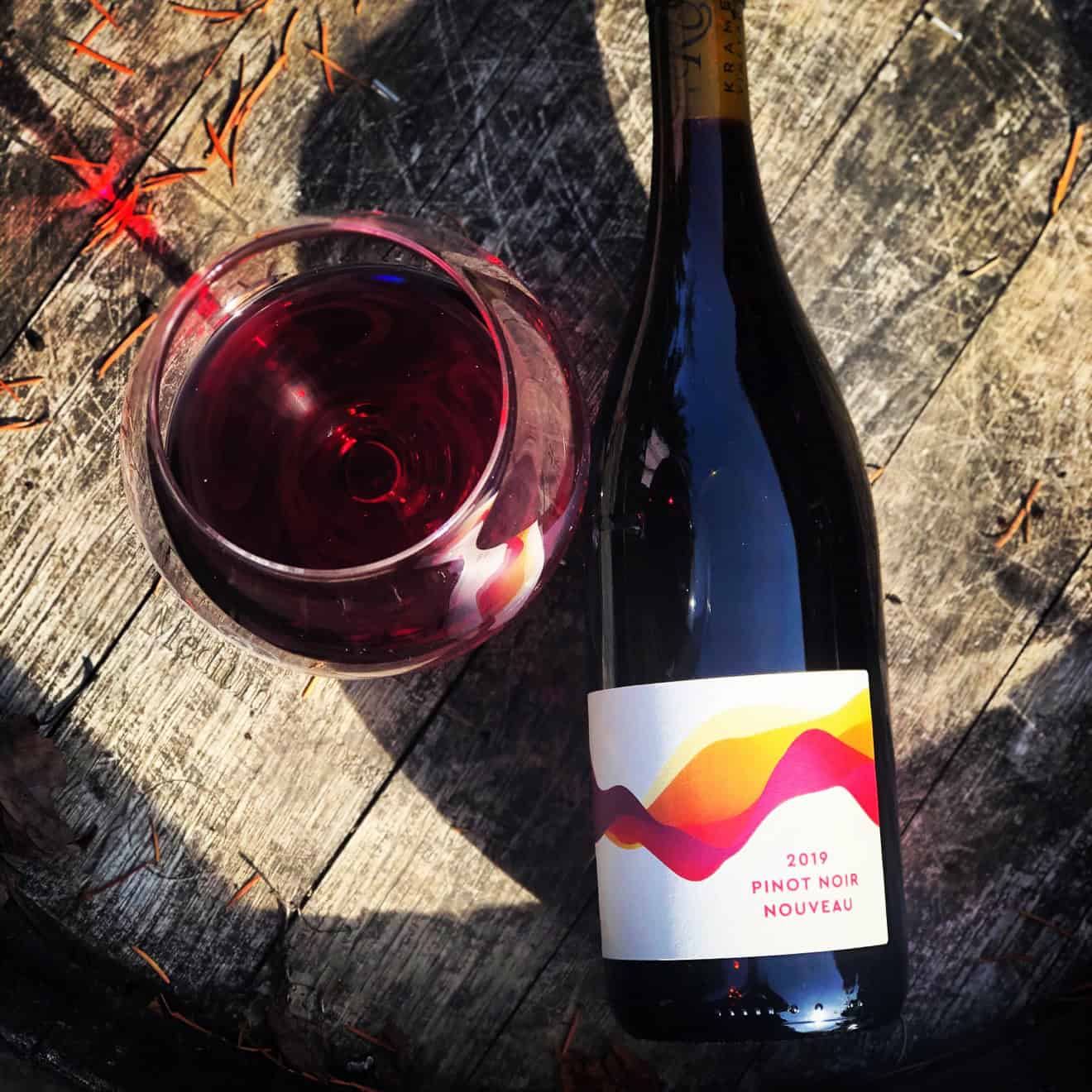 Nouveau Day 1 A glass of Kramer Vineyards Pinot Noir Nouveau beside the bottle, on a barrel in the autumn sun